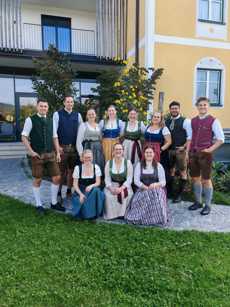 Trachtengruppe posiert vor gelbem Haus in Österreich